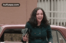 a woman is walking towards a car while holding a purse .