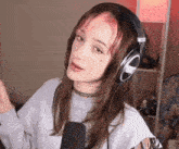 a young woman with pink hair is wearing headphones and a choker .