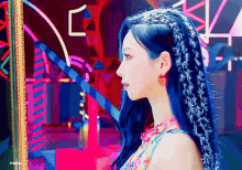a woman with blue hair and a heart shaped earring is standing in front of a mirror