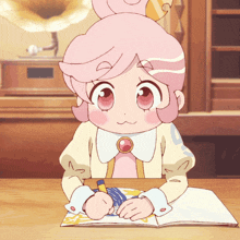 a girl with pink hair is sitting at a table with a book in front of her