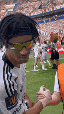 a man wearing sunglasses and a headband shakes hands with another man