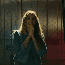 a woman in a denim jacket is standing in front of a red and blue wall