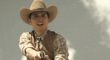 a man wearing a cowboy hat is pointing a gun at the camera