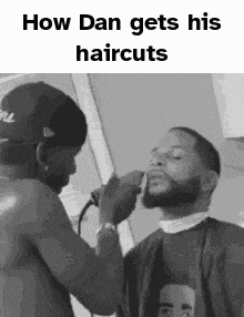 a black and white photo of a man getting his hair cut by another man