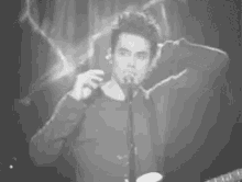 a man is singing into a microphone while holding a guitar