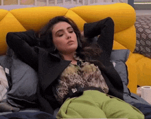 a woman is laying on a yellow couch with her arms behind her head
