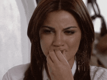 a woman covering her mouth with her hand in a white shirt