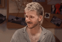 a man with a mullet and a beard looks at the camera