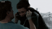 a man talking on a cell phone with bbc written on the bottom