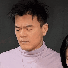 a man in a purple turtleneck is looking down