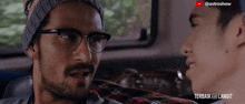 a man wearing glasses and a beanie is talking to another man in a video that says terbaik menjadi langit