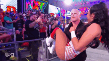 a man is carrying a woman in his arms in front of a crowd with usa written on the bottom