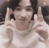 a man in a white sweater is making a peace sign with his hands