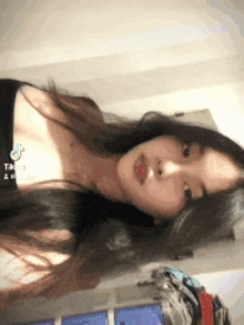 a woman with long black hair is taking a selfie with a tiktok app on her phone .