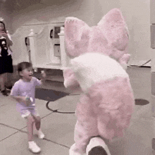 a little girl is standing next to a stuffed animal in a room .