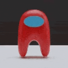 a red among us character with a blue face is sitting on a table .