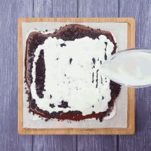 a cutting board with a piece of chocolate cake with whipped cream on top