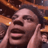 a close up of a man 's face with his hands on his ears
