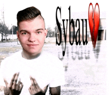 a young man in a white shirt stands in front of a sign that says sybau