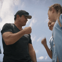 a man wearing a black shirt and a black hat talks to two young girls