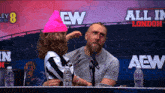 a man and a little girl are sitting in front of a sign that says aew