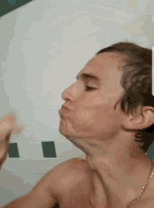 a man without a shirt is taking a shower and making a face