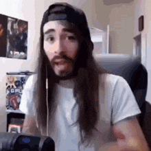 a man with long hair and a beard is sitting in front of a microphone wearing headphones .