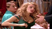 a woman in a green dress is sitting at a table talking to a man