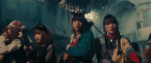 a group of girls are standing next to each other in a dark room holding guns .