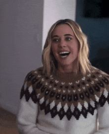 a woman wearing a sweater with a pattern on it is smiling