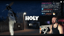 a man sitting in front of a screen that says holy on it
