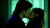a man and a woman kiss in front of a window