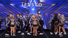 a group of cheerleaders are dancing on stage in front of a star .