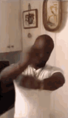 a man in a white shirt is standing in a kitchen holding a pillow .