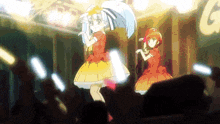 two anime girls are performing on stage in front of a crowd .