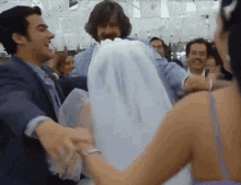 a man in a suit is carrying a woman in a wedding dress on his shoulders .