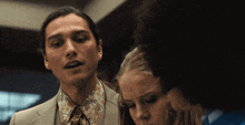 a man in a suit talks to two women
