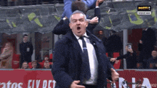 a man in a suit and tie is being lifted in the air by another man on a soccer field