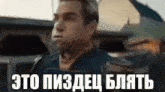 a man in a black jacket is standing in front of a building with a sign in russian .