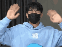 a man wearing a black mask and a blue hoodie with the word wang on it
