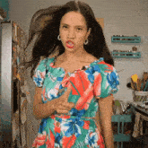 a woman in a colorful floral dress is giving a thumbs up