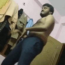 a shirtless man is standing in front of a closet full of clothes .