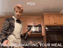 a man in an apron is standing in front of a microwave with the caption " you are awaiting your meal " below him