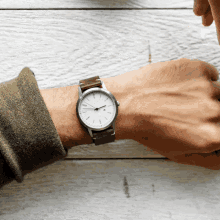 a man wearing a watch on his wrist that shows the time as almost 5:00