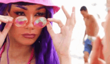 a woman with purple hair and sunglasses is making a peace sign