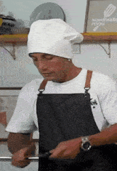 a man wearing a chef 's hat and apron prepares food in front of a homemade food sign