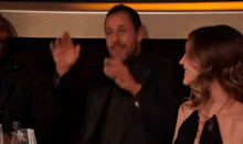 a man in a black suit says " chalamet " in front of a woman
