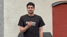 a man wearing a black t-shirt that says " aion " on it