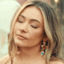 a close up of a woman 's face with her eyes closed wearing earrings