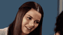 a woman with long brown hair is smiling and looking at the camera